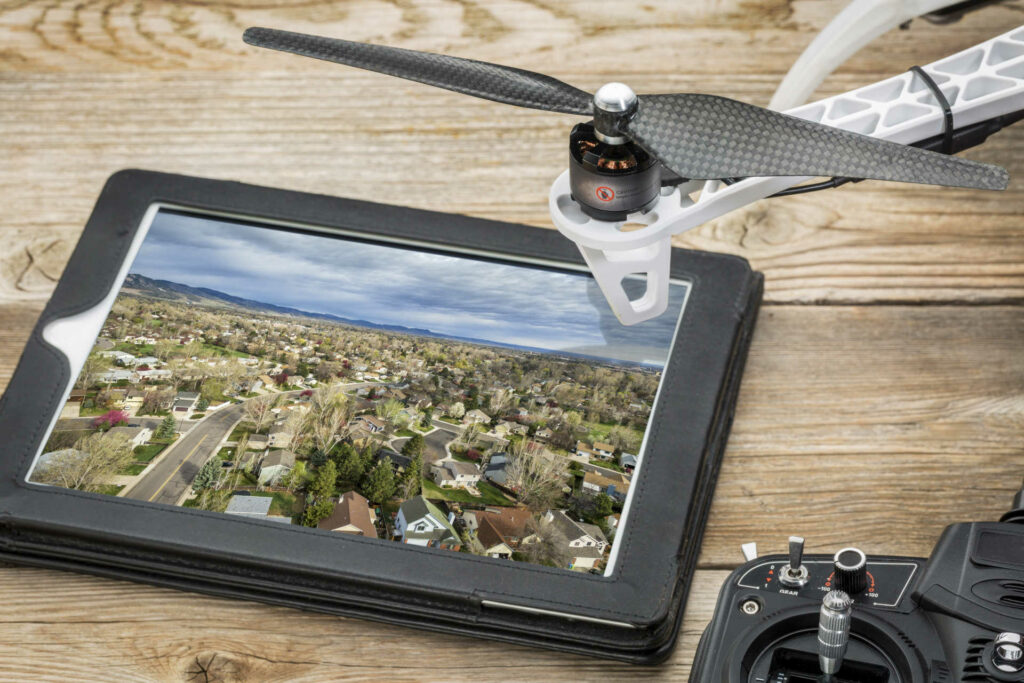 drone aerial photography concept - reviewing aerial picture of residential area on a digital tablet with a drone rotor and radio control transmitter,